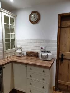a kitchen with a counter with a clock on the wall at Cosy Cottage, in the idyllic town of Holt in Holt