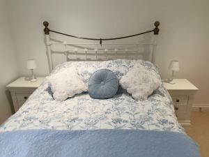 a bed with a blue pillow and pillows on it at Cosy Cottage, in the idyllic town of Holt in Holt