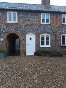 a brick house with a white door with a arrow on it at Cosy Cottage, in the idyllic town of Holt in Holt +8 photos