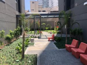 a courtyard with red chairs and trees in a building at Loft aconchegante com piscina a um passo do metrô in Sao Paulo