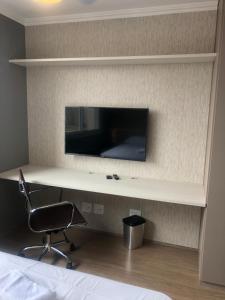 a bedroom with a desk with a chair and a tv at Loft aconchegante com piscina a um passo do metrô in Sao Paulo
