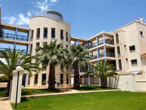 a building with palm trees in front of it at Regia Bahia en Cabo Roig in Orihuela Costa