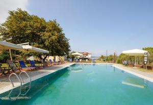 a large swimming pool with chairs and umbrellas at Villa Vasiliadi in Vourvourou