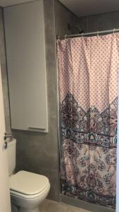 y baño con aseo y cortina de ducha. en Cómodo apartamento frente al Mar en Piriápolis