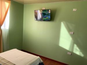 a green room with a bed and a picture on the wall at Hospedaje La ruta Los Angeles in Los Ángeles