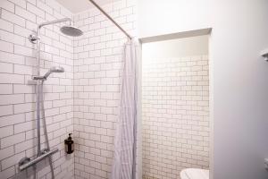 a white tiled shower with a shower curtain in a bathroom at The Churchill 4 - Into This Place in Copenhagen