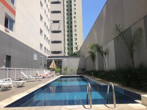 a swimming pool with chairs and a building at Loft aconchegante com piscina a um passo do metrô in Sao Paulo