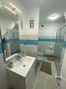 łazienka z umywalką, toaletą i lustrem w obiekcie Zaffiro casa vacanze al mare w mieście Valledoria