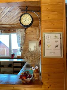 um relógio pendurado por cima de um balcão de cozinha com uma taça de fruta em Faina House em Yaremche