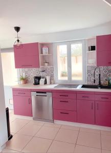 uma cozinha com armários cor-de-rosa e uma janela em Maison La demoiselle de Chambord em Huisseau-sur-Cosson