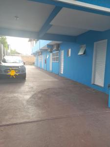 a car parked in a parking lot next to a blue building at Pousada Ancoradouro in Cananéia
