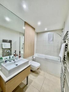 Gunwharf Quays Harbour Apartments في بورتسماوث: حمام مع حوض ومرحاض وحوض استحمام