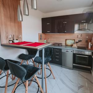 a kitchen with black cabinets and a table with stools at Apartman Orhideja with Free Parking in Sarajevo