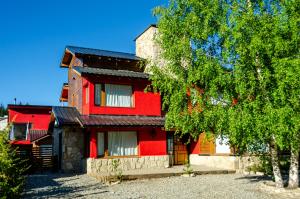 ein rotes Haus mit einem Baum davor in der Unterkunft Kurtem Lodge in San Carlos de Bariloche