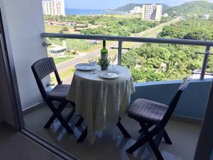 ein Tisch mit einer Weinflasche und zwei Stühlen auf einem Balkon in der Unterkunft Pozos Colorados Santa Marta - Apartamento 1005 hermosa vista in Santa Marta