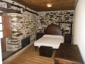 um quarto com uma cama e uma parede de pedra em Casa Rural Los Cabritos de Tomás em Puebla de Sanabria