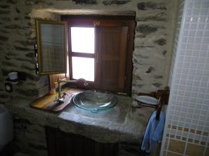 Baño de piedra con lavabo y ventana en Casa Rural Los Cabritos de Tomás, en Puebla de Sanabria