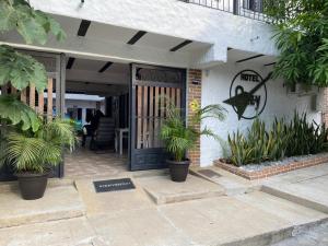 Hotel Ozzy في Doradal: باب أمام منزل به نباتات الفخار