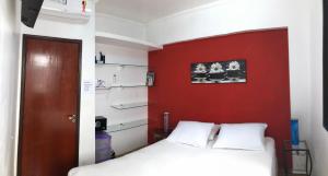 una camera con un letto e una parete con accento rosso di APTO M DE SÁ AR CONDICIONADO a Caraguatatuba