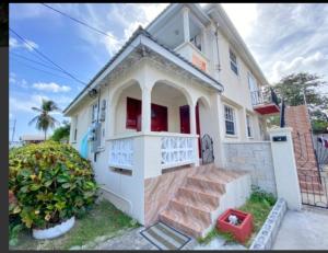 a white house with a staircase in front of it at Carmen Apartment in Bridgetown