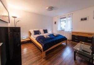1 dormitorio con cama con sábanas azules y ventana en ERZHAUS Apartments en Eisenerz