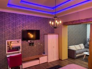 a living room with a tv on a purple wall at Tošić apartman in Sombor