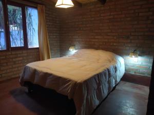 1 dormitorio con 1 cama grande en una pared de ladrillo en Piedra Campana alojamiento en Tilcara