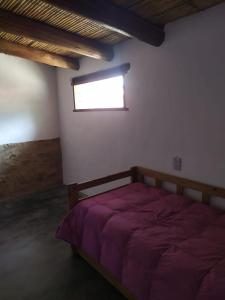 a bedroom with a bed with a window in it at Piedra Campana alojamiento in Tilcara