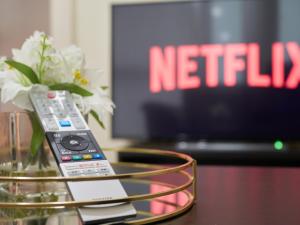 a remote control sitting on a table with a vase of flowers at Cosy One Bed City Apartment -The Hub in Milton Keynes