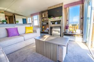 ein Wohnzimmer mit einem Sofa und einem Kamin in der Unterkunft Sea 'n' Stars Platinum Plus Holiday home with Views, Free Wifi and Netflix in Camber