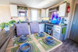 a kitchen with a table with plates and glasses on it at Sea 'n' Stars Platinum Plus Holiday home with Views, Free Wifi and Netflix in Camber