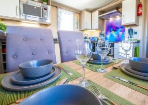 a table with plates and wine glasses on it at Sea 'n' Stars Platinum Plus Holiday home with Views, Free Wifi and Netflix in Camber