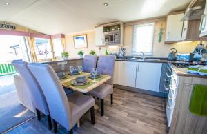 a kitchen with a table and chairs in a kitchen at Sea 'n' Stars Platinum Plus Holiday home with Views, Free Wifi and Netflix in Camber