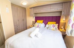 a bedroom with a large white bed with yellow accents at Sea 'n' Stars Platinum Plus Holiday home with Views, Free Wifi and Netflix in Camber