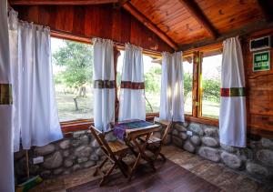 a room with a table and chairs and windows at Aguada Escondida in San Marcos Sierras