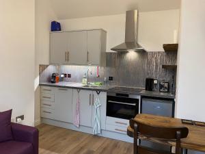 a kitchen with white cabinets and a counter top at Butterfly Cottage in Grantown on Spey