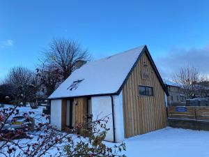 a small wooden building with snow on top of it at Butterfly Cottage in Grantown on Spey