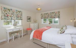 a bedroom with a bed and a desk and two windows at Overbrook in Droitwich