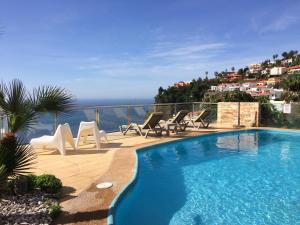 una piscina con sedie e vista sull'oceano di Villa Isabela - Car Rental for Free a Caniço