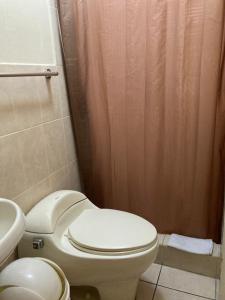 La salle de bains est pourvue de toilettes et d'un rideau de douche. dans l'établissement Comfort Hostel, à Guatemala