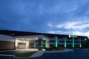 een ziekenhuisgebouw met groene lichten op een parkeerplaats bij Holiday Inn - Long Island - ISLIP Arpt East, an IHG Hotel in Holtsville