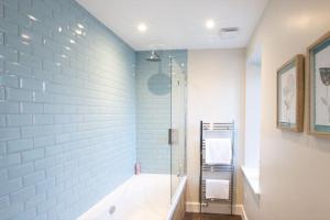 a bathroom with a shower and a bath tub at Stunning Edinburgh 1820s stables converted house in Ratho