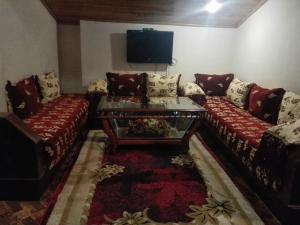 un soggiorno con 2 divani e una TV di appartement chalet a Imouzzer Kandar