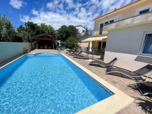 a swimming pool with chairs and a house at Holiday home in Jadranovo 42254 in Jadranovo