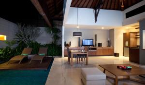 a living room with a table and a kitchen at Pradha Villas Seminyak in Seminyak