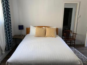 1 dormitorio con 1 cama blanca grande con almohadas en Black Rooster Guesthouse, en Prince Rupert