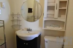 a bathroom with a sink and a mirror and a toilet at Black Rooster Guesthouse in Prince Rupert