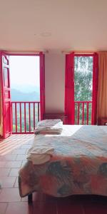 a bedroom with a bed and two large windows at Hotel Natura Cocora in Salento