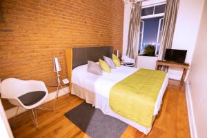 a bedroom with a bed and a brick wall at New Voga Hotel Boutique in Valparaíso