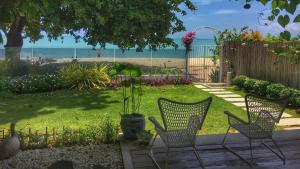 a yard with two chairs and a table and the beach at Smell rose beach garden in Batu Ferringhi